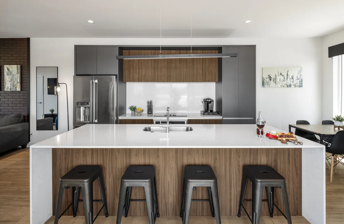 A functional, stylish kitchen with a large island, stainless steel appliances, wood cabinetry, and decorative touches. The scene suggests both practicality and a warm, home-like feeling, with plenty of counter space and quality finishes.