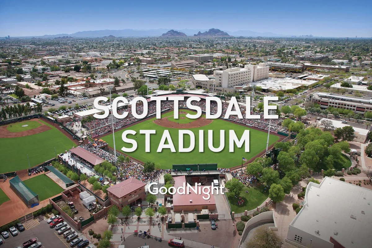 An energetic baseball stadium filled with fans, a green field, and the scenic landscape beyond. The image conveys excitement, social interaction, and the atmosphere of live events at Scottsdale Stadium.