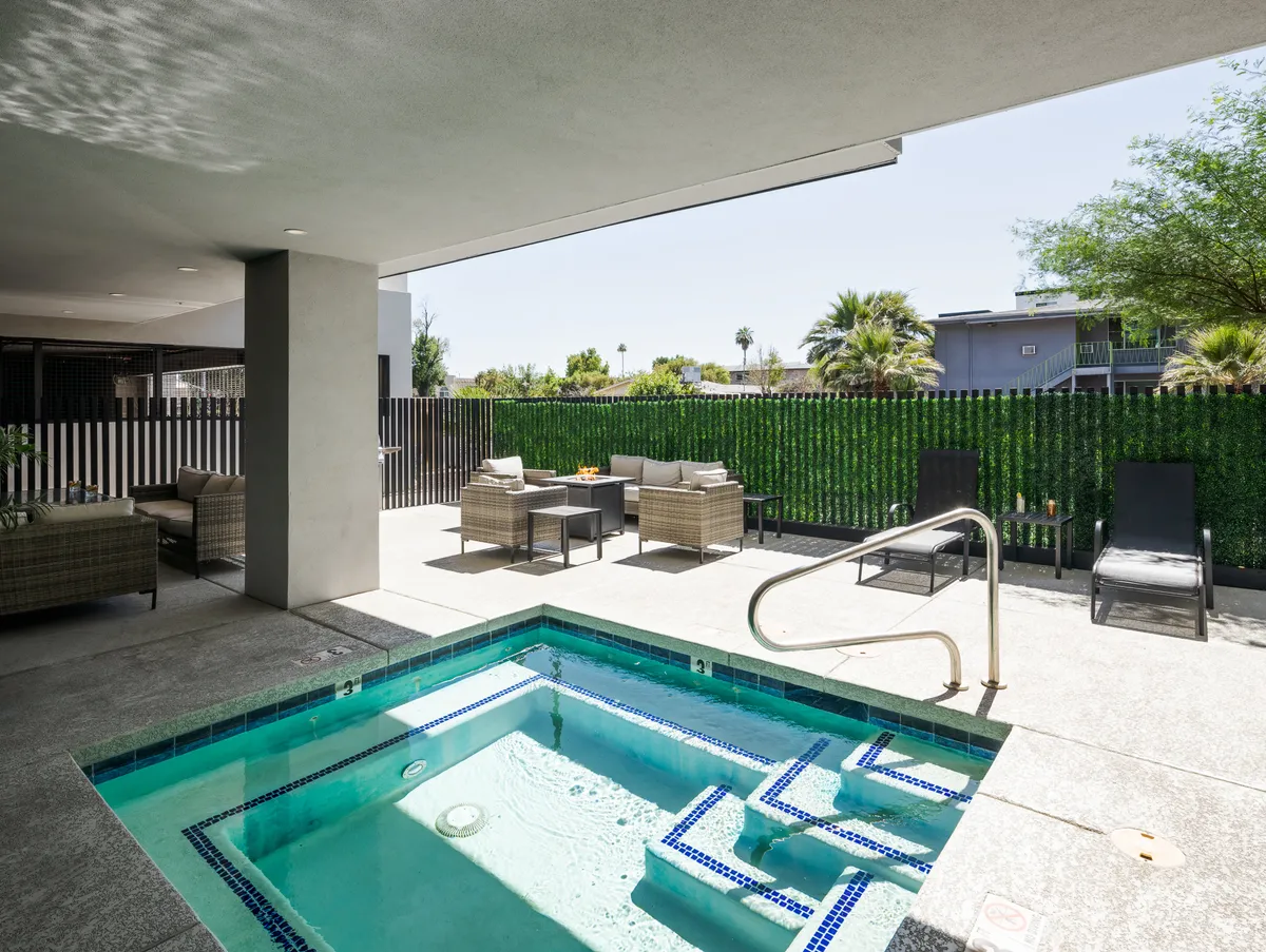 A luxurious exterior swimming pool area surrounded by comfortable outdoor seating, lush green foliage, and modern architectural lines. The scene is designed for both relaxation and group gatherings, with spaces that invite sunbathing, entertaining guests, and enjoying meals outdoors.