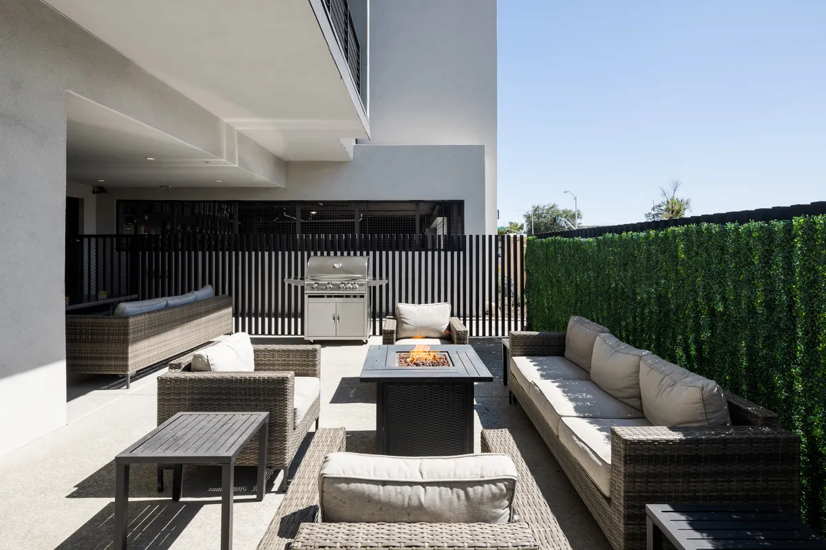A contemporary outdoor oasis featuring a fire pit surrounded by cozy seating, a barbecue grill, and lush vertical garden. The setting is perfect for sunset gatherings, alfresco dining, and socializing under the stars.